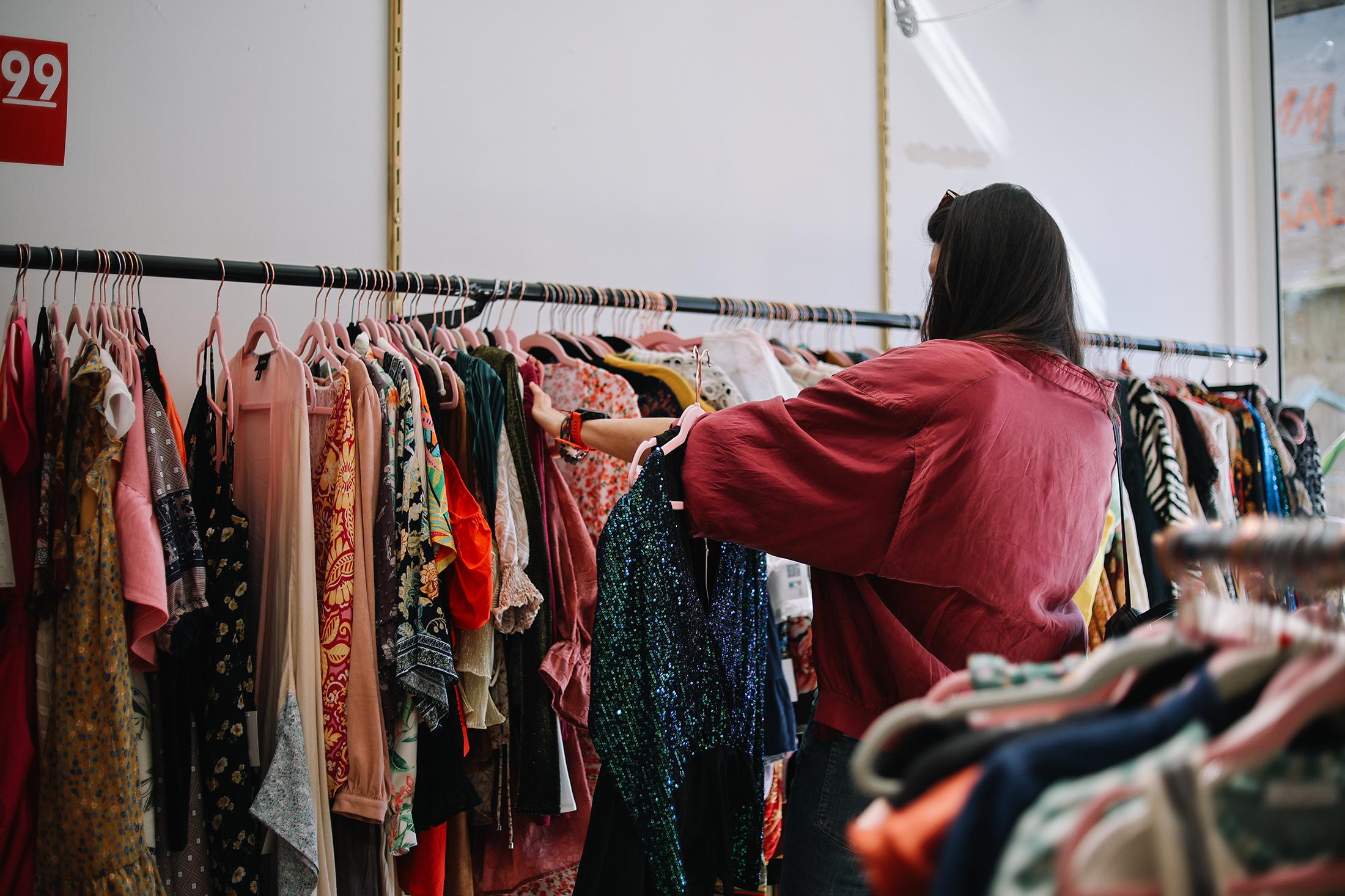 Thrift store worker near a rack of clothing